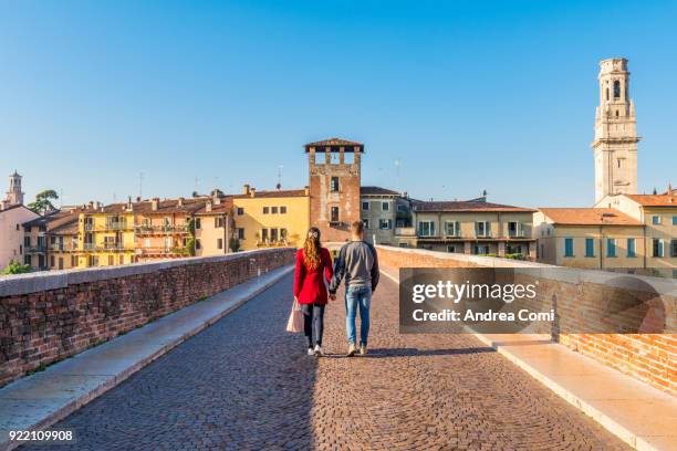 a young couple walking on ponte pietra. verona, veneto, italy - verona italy stock pictures, royalty-free photos & images