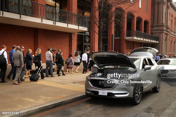 People walk past a formerly suspicious vehicle with its hood and tailgate open as they wait to enter the New Executive Office Building near the White...