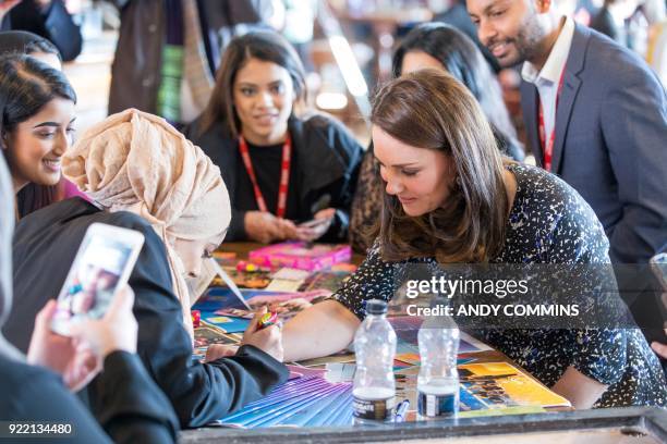 Britain's Catherine, Duchess of Cambridge gets a henna tattoo on her hand as she visits The Fire Station, an iconic building recently converted into...