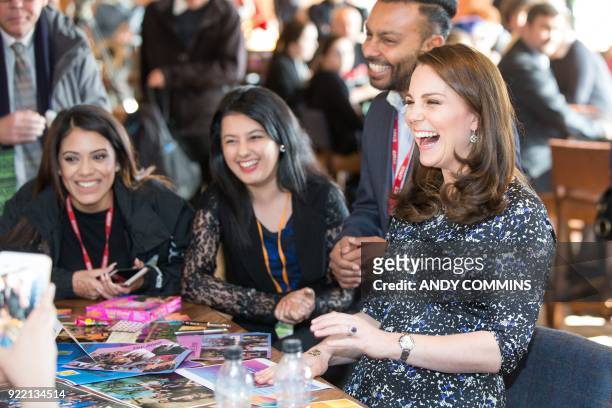 Britain's Catherine, Duchess of Cambridge, laughs as she after getting a henna tattoo on her hand during a visit to The Fire Station, an iconic...