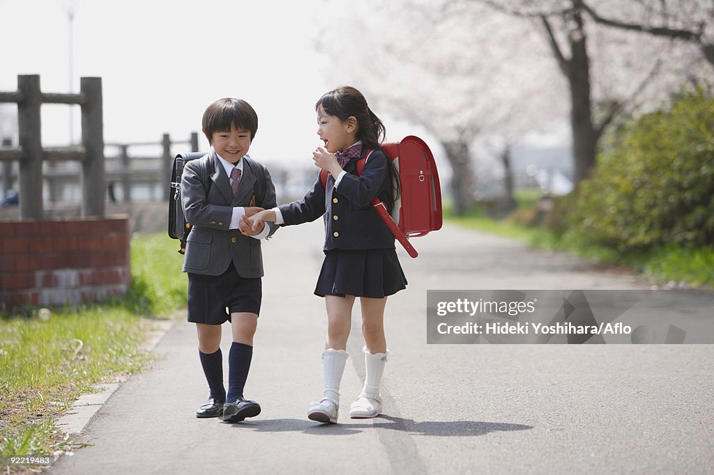 Schoolmate holding hands and walking together 