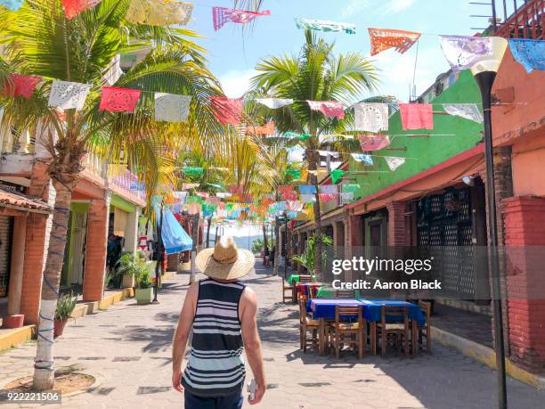 tourist with straw hat walks down street under colourful papel picador. - picador stock-fotos und bilder
