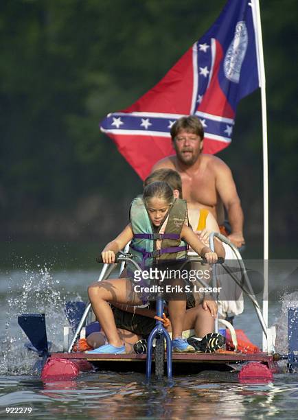 Participants in the Oconee River Raft Race peddle their raft down the river during the Seventh Annual Summer Redneck Games July 6, 2002 in East...
