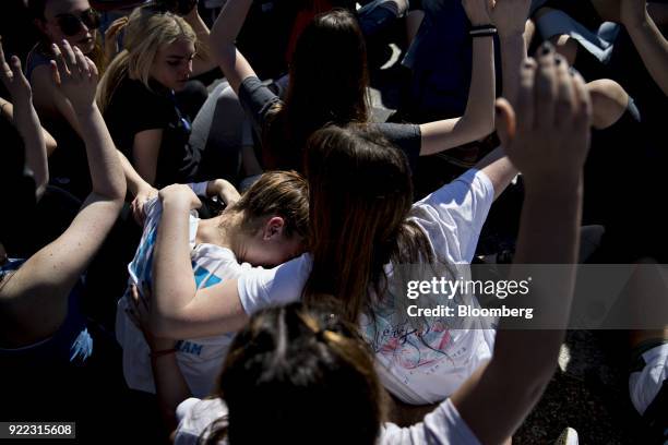 Demonstrator is consoled as students hold their hands up during a moment of silence while reading the names of victims from last weeks high school...