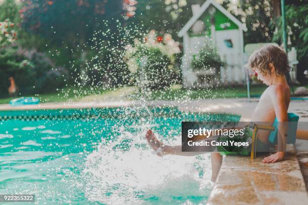 boy in swimsuit splashing in poolside in summer - agua estancada fotografías e imágenes de stock