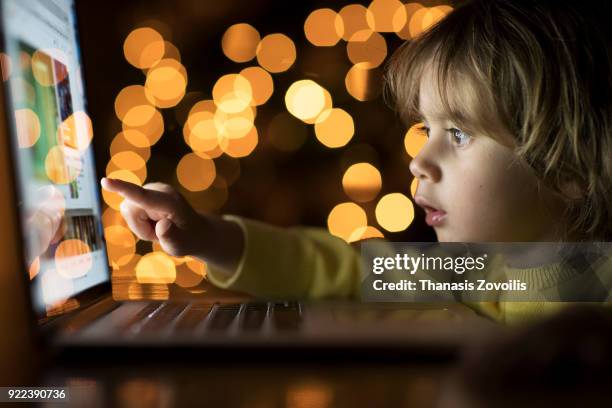 2 year old boy looking a laptop in the dark - thanasis zovoilis stock pictures, royalty-free photos & images