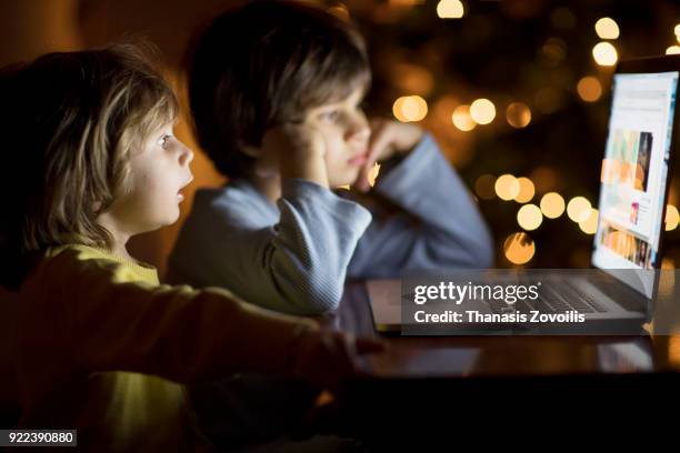 kids looking a laptop in the dark - thanasis zovoilis stock pictures, royalty-free photos & images