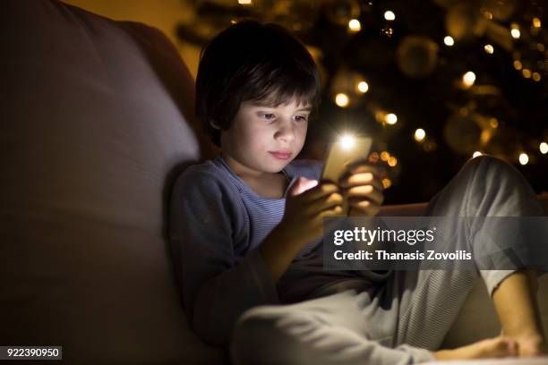 6 year old boy looking a smart phone in the dark - thanasis zovoilis stock pictures, royalty-free photos & images