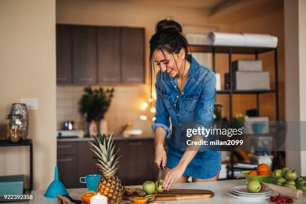 young woman preparing juice from fruit in her kitchen - pineapple cut stock pictures, royalty-free photos & images