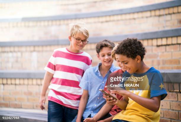 boys looking at friend using mobile phone - 13 year old cute boys stock pictures, royalty-free photos & images