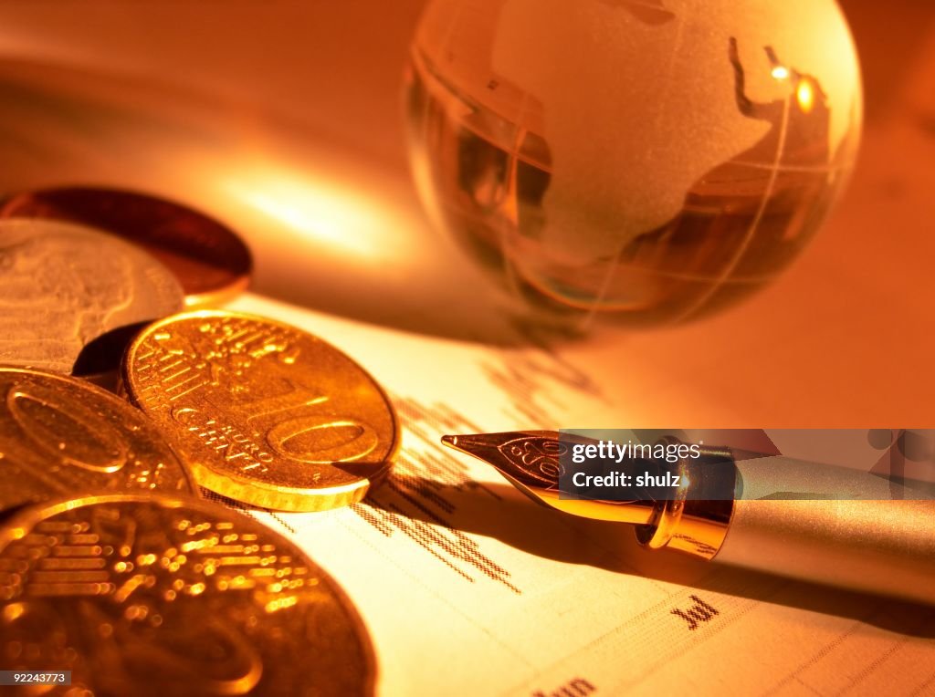 Crystal globe, coins and fountain pen on the stock page