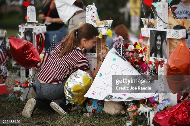 Victoria Seltzer writes a passage on a cross setup in a makeshift memorial in front of Marjory Stoneman Douglas High School in memory of the 17...