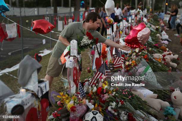 Greg Stein places flowers in a makeshift memorial setup in front of Marjory Stoneman Douglas High School in memory of the 17 people that were killed...