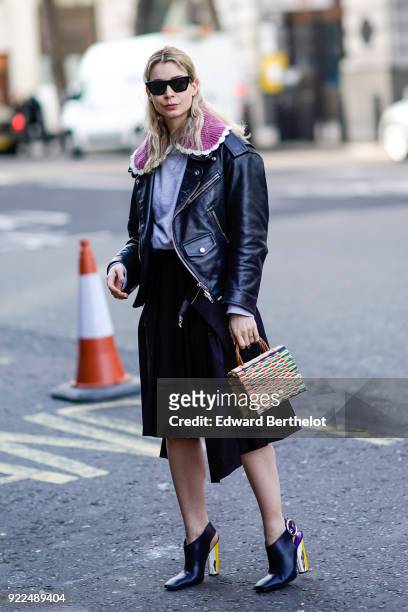 Irina Lakicevic wears sunglasses, a black leather jacket, a bag, a skirt, during London Fashion Week February 2018 on February 16, 2018 in London,...