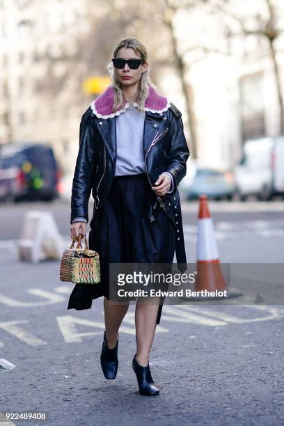 Irina Lakicevic wears sunglasses, a black leather jacket, a bag, a skirt, during London Fashion Week February 2018 on February 16, 2018 in London,...