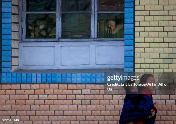 North Korean pioneer girl carrying her brother on her back, Kangwon Province, Wonsan, North Korea on May 1, 2010 in Wonsan, North Korea.