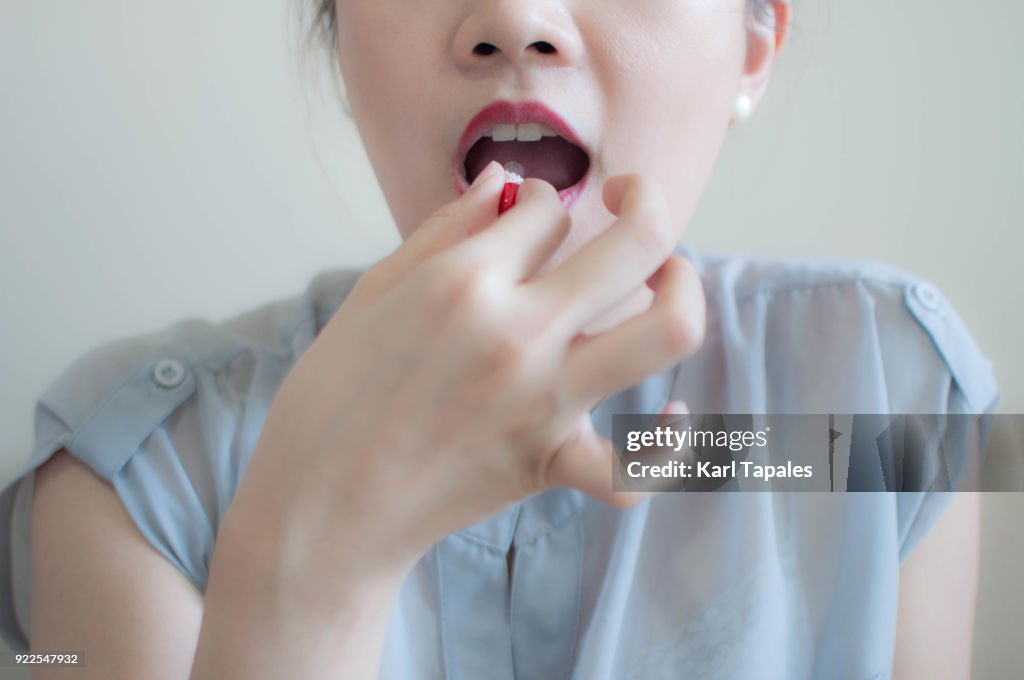 A woman is taking a medicine capsule