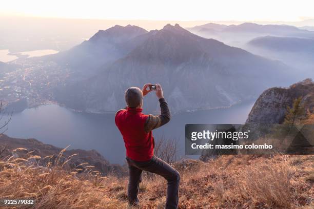 hiker take a pic on mountain - mann auf berg mit smartphone stock-fotos und bilder