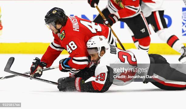 Johnny Oduya of the Ottawa Senators and Vinnie Hinostroza of the Chicago Blackhawks hit the ice as they battle for the puck at the United Center on...