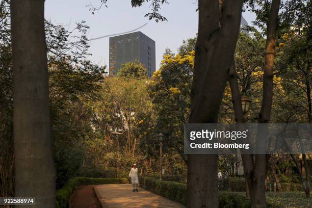 Man walks along a park path as the Trump Towers Pune complex, developed by Panchshil Corp Park Pvt., stands in the distance in Pune, Maharashtra,...