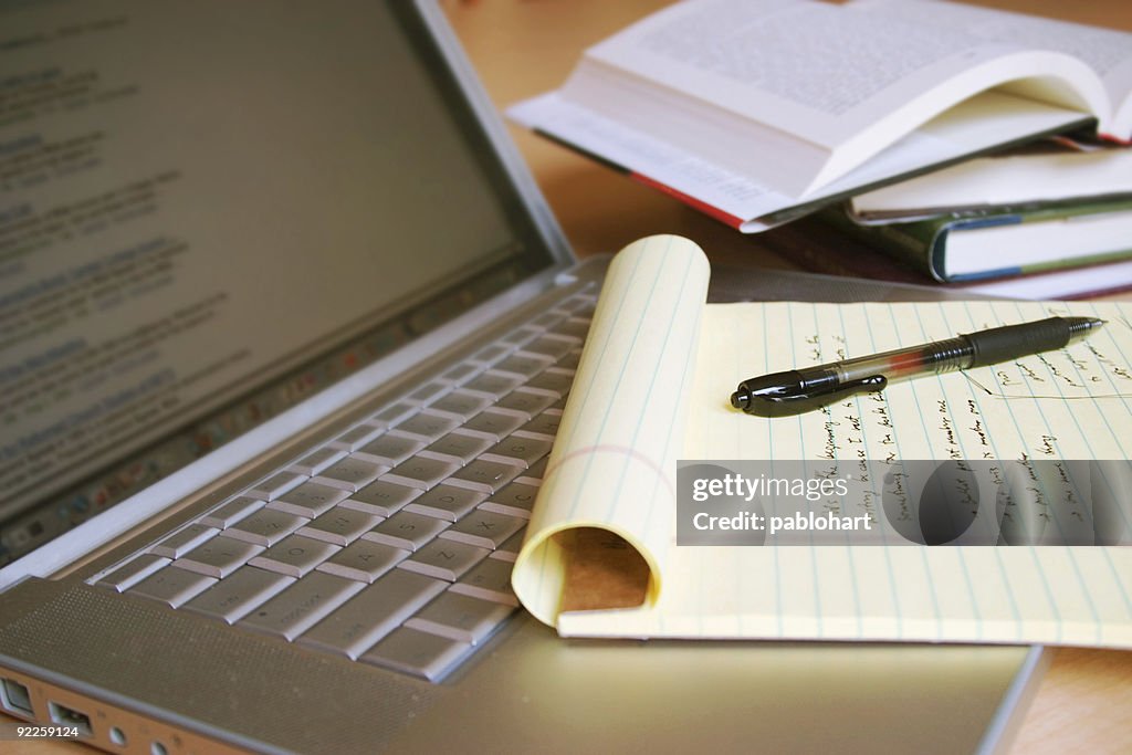 Laptop computer with books, pen and yellow legal pad