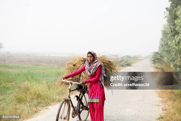 indian women riding cycle on country road - poor farmer stock pictures, royalty-free photos & images