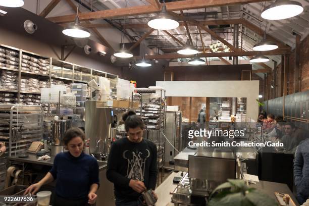 Workers prepare chocolate dishes in a gleaming open kitchen as guests sit along a bar at Dandelion Chocolate, a small-batch chocolate roaster in the...