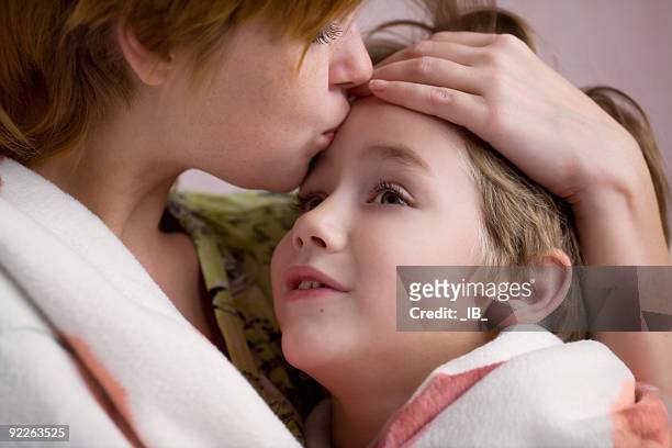 mother kissing her son on the forehead - compassionate eye stockfoto's en -beelden