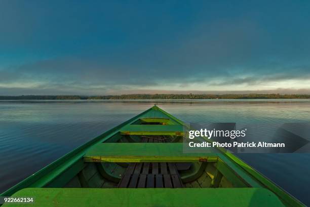 green boat crossing the rio negro river at sunrise in the amazon region, anavilhanas natural reserve, amazonas, brazil - manaus stock pictures, royalty-free photos & images