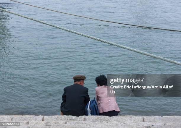 North Korean couple sit in front of Taedong river, Pyongan Province, Pyongyang, North Korea on May 9, 2010 in Pyongyang, North Korea.