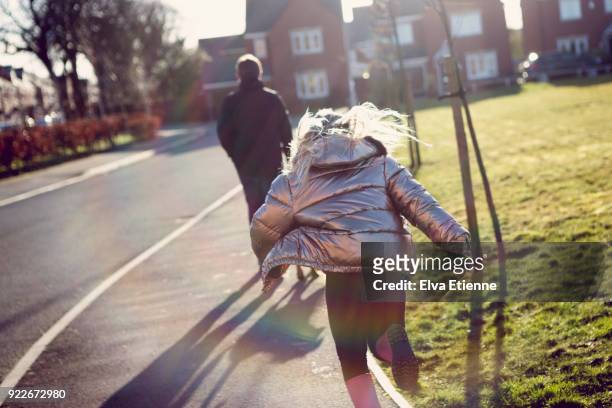 girl running towards teenage boy, on the sidewalk of a residential street in the uk - seguir actividad móvil general fotografías e imágenes de stock