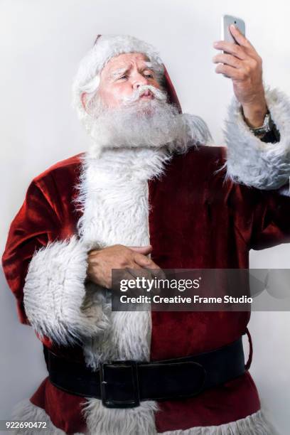 candid santa claus using a smartphone - selfie - video call - one finger selfie stock-fotos und bilder