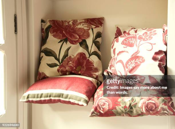 cushions by a window - a woman modelling a trouser suit blends in with a matching background of floral print cushions stockfoto's en -beelden