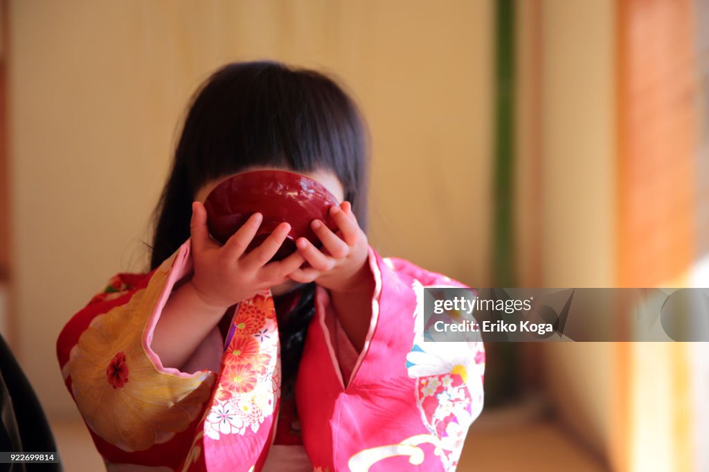 2 years old girl imitating to drink New year's spiced sake called Otoso