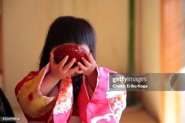 2 years old girl imitating to drink new year's spiced sake called otoso - kimono winter stock pictures, royalty-free photos & images