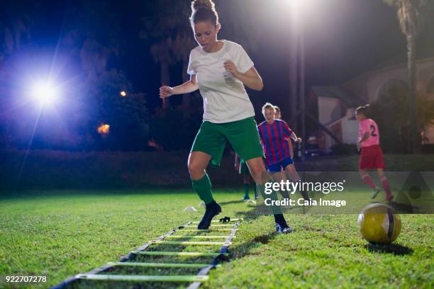 young female soccer players practicing agility sports drill on field at night - agility ladder stock-fotos und bilder