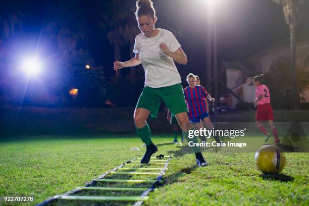 young female soccer players practicing agility sports drill on field at night - agility ladder stock pictures, royalty-free photos & images