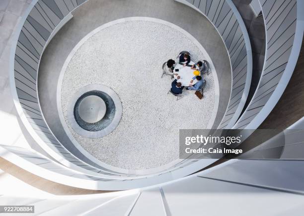 view from above business people meeting at table in round modern atrium courtyard - distant stock pictures, royalty-free photos & images