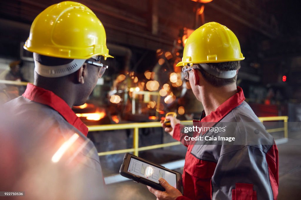 Supervisor and steel worker with digital tablet working in steel mill