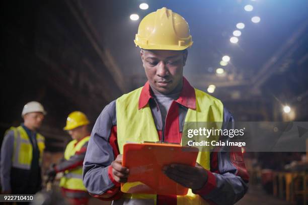 steelworker with clipboard working in steel mill - flouté photos et images de collection