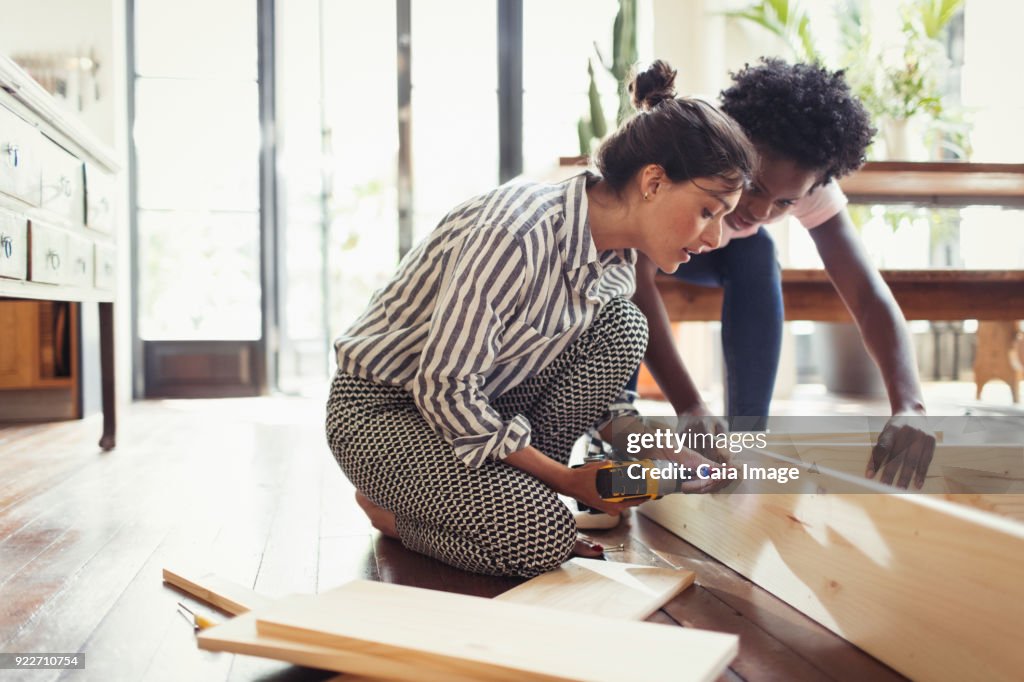 Young women assembling furniture with power drill