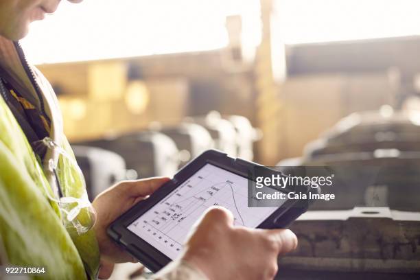 close up steelworker reviewing digital graph on digital tablet in steel mill - assessment graph stock-fotos und bilder