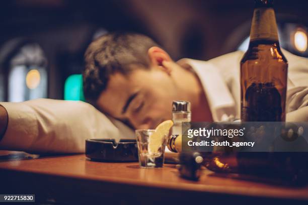 junger mann betrunken schlafen auf bartheke - betrunken stock-fotos und bilder