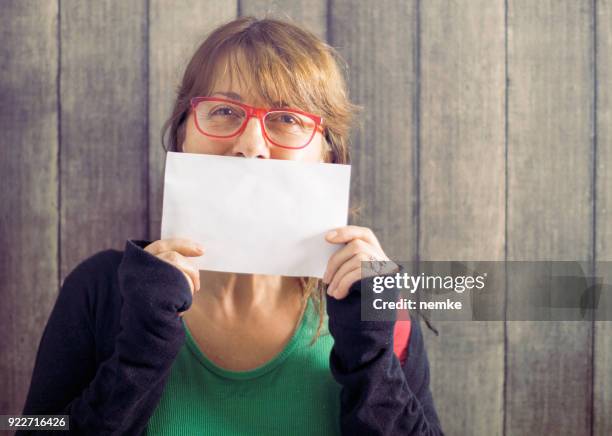 donna matura di mezza età che tiene la scheda bianca - portrait holding card foto e immagini stock