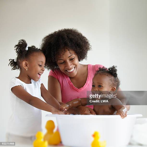 mother and daughter giving baby girl a bath - mother and baby taking a bath stock pictures, royalty-free photos & images