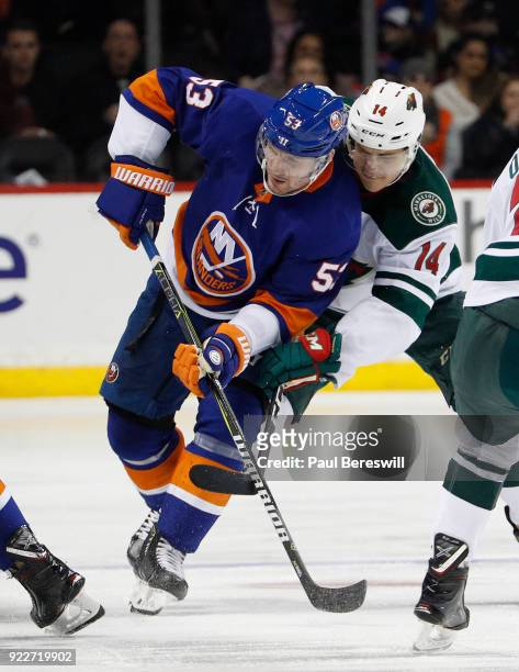 Casey Cizikas of the New York Islanders and Joel Eriksson Ek of the Minnesota Wild try to control the puck on a faceoff in an NHL hockey game at...
