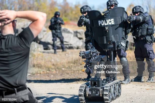 police swat team officers using a mechanical robot unit - police in riot gear stock pictures, royalty-free photos & images