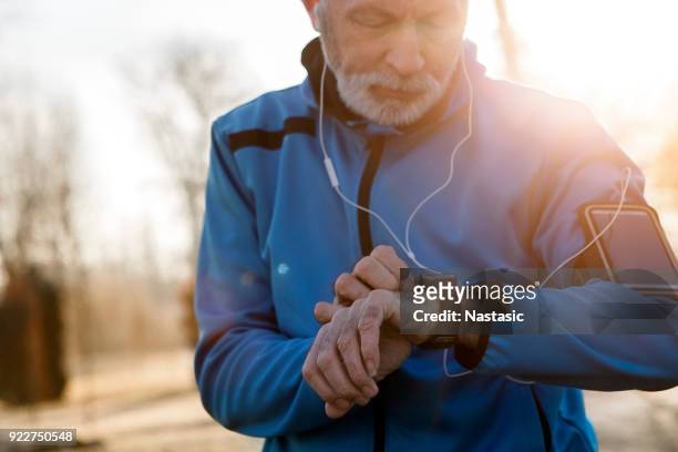 senior-mann mit smart watch, die messung der herzfrequenz - running man heartbeat stock-fotos und bilder