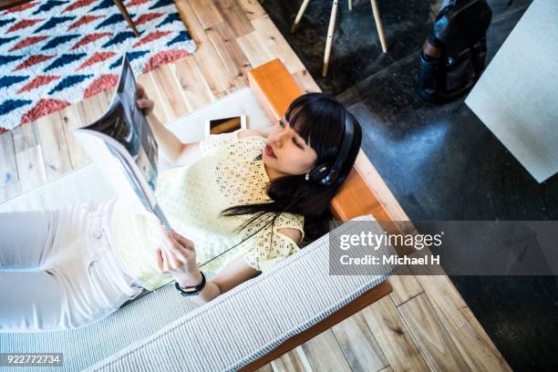 woman relaxing on sofa with magazine - holding magazine stock-fotos und bilder