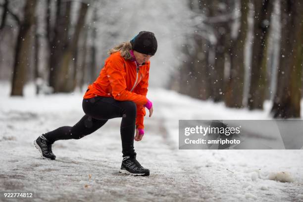 eine frau, die dehnung in schneereichen winter gasse - european sports pictures of the month december stock-fotos und bilder